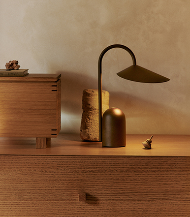 Lampade da tavolo eleganti e dal design scultoreo, perfette per creare un’illuminazione d’atmosfera su una credenza in legno naturale.