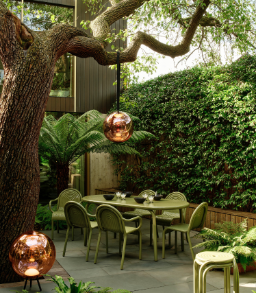 Lampade da esterno Tom Dixon in un elegante giardino con zona pranzo sotto un vecchio albero.