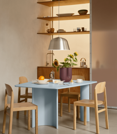 Zona pranzo minimalista con lampada a sospensione moderna, mensole in legno e tavola apparecchiata.