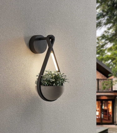 Applique con fioriera integrata e luce calda su una facciata chiara.