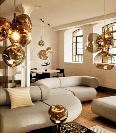 Lampade a sospensione Melt color oro sopra un divano chiaro in un loft con finestre a riquadri.